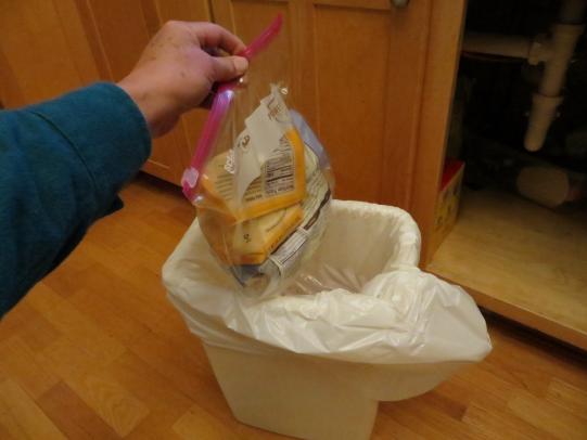 Sealed bag being dropped in trash can