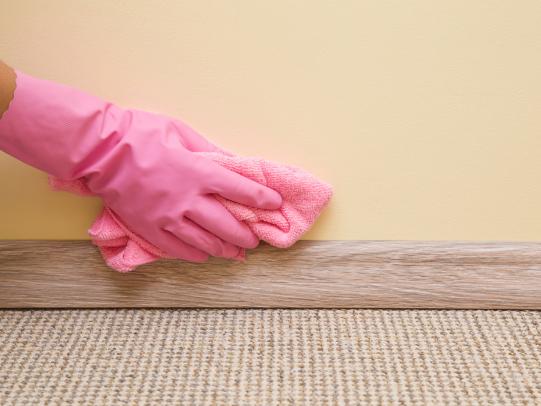 Gloved hand cleaning baseboards