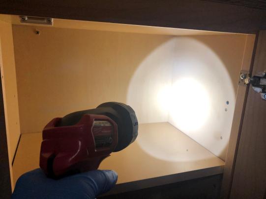 Flashlight used to inspect cabinet crevices