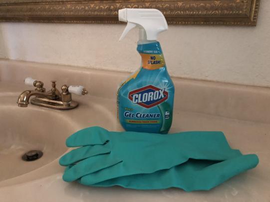 Bleach product and gloves near bathroom sink