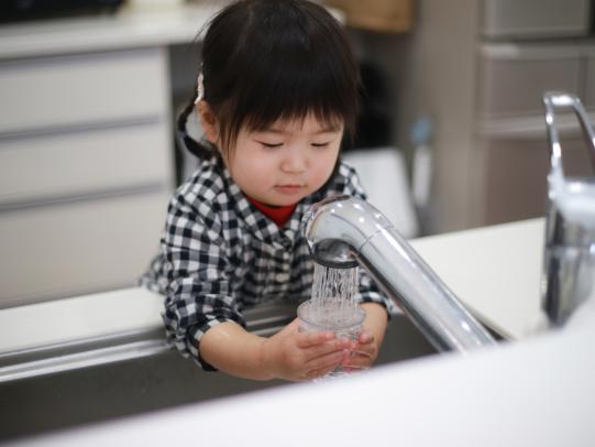 Child filling water glass from faucet