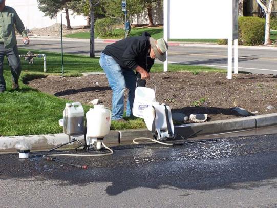 Landscape worker mixing pesticides in street gutter