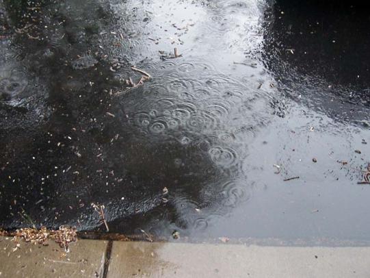 Raindrops falling on flooded concrete and asphalt