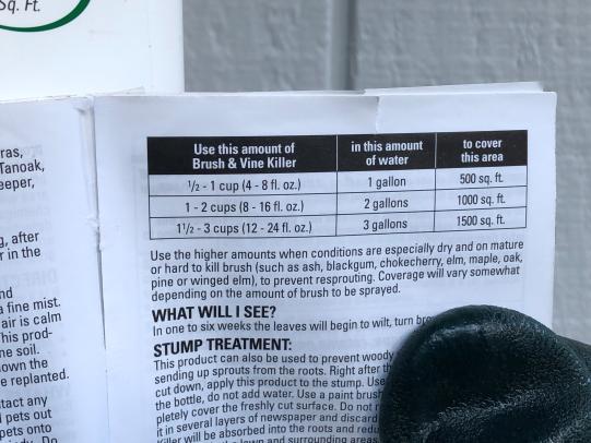 Gloved finger pointing to application rate table on pesticide label