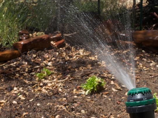 Sprinkler spraying water on bare ground