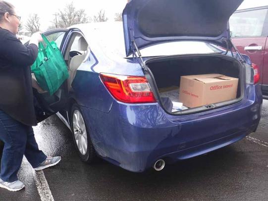 A person storing pesticides in a box in the trunk and groceries in the car